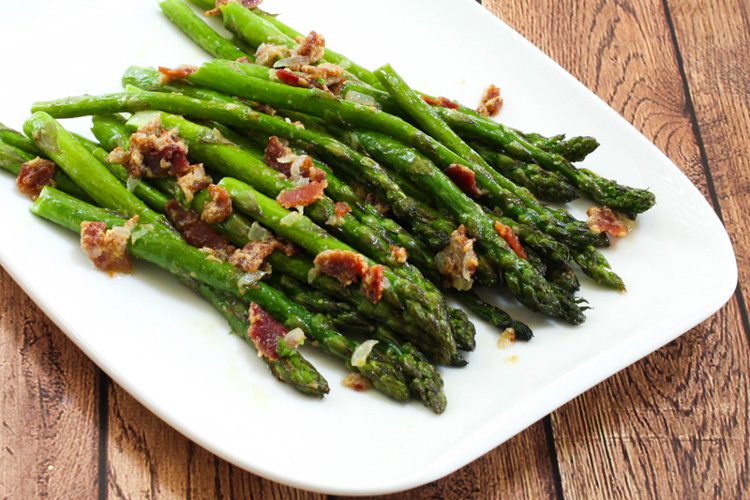 a plate of asparagus with bacon and light mustard sauce for flavor
