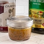 Jar of seasoned marinade with spices and herbs.