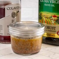 Jar of seasoned marinade with spices and herbs.