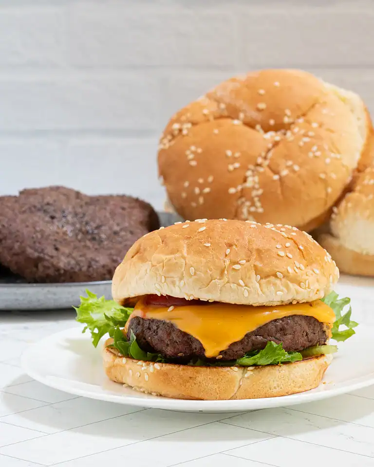 Golden sesame seed bun with a juicy cheeseburger and fresh lettuce.