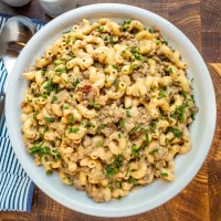 Creamy macaroni and sausage pasta garnished with chopped chives.