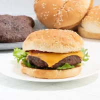 Flavored cheeseburger with lettuce and cheese on a sesame bun.