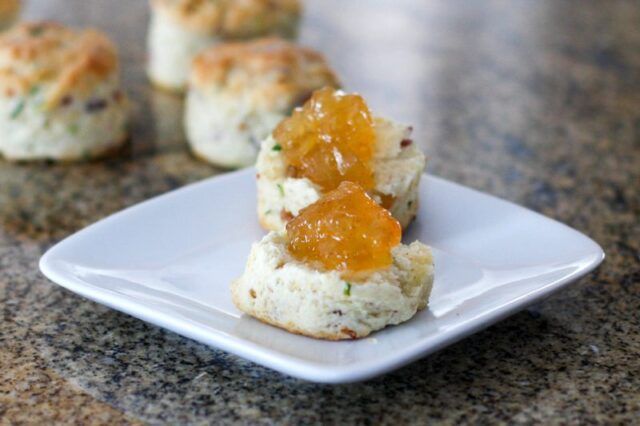 bacon and chive biscuits on a plate, topped with marmalade.