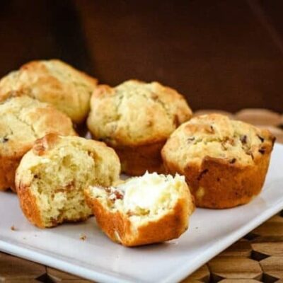 bacon muffins on a square plate, one is buttered