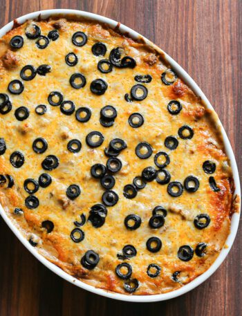 Overhead photo of a beef enchilada casserole with a topping of cheese and black olives.