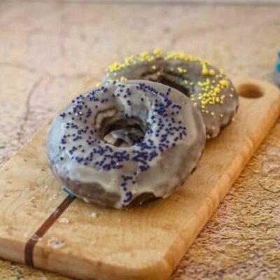 baked chocolate donuts with glaze and sprinkles on a small cutting board