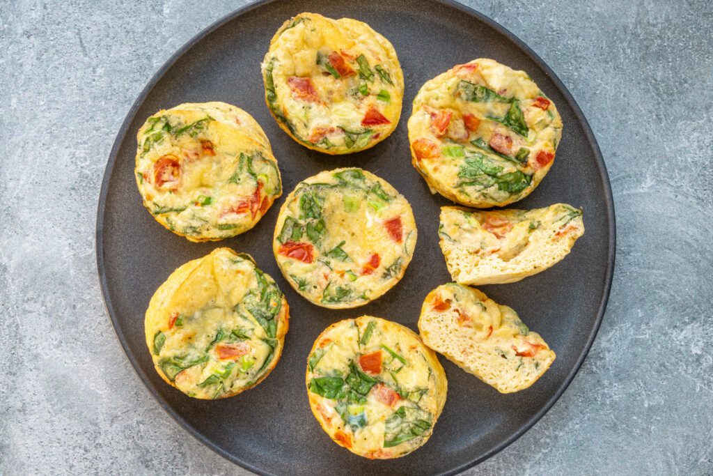 tomato, spinach, bacon, and cheese egg bites on a plate