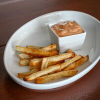 Baked French fries in a plate with sriracha mayo dip.