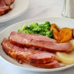 sliced baked ham on a plate with side dishes