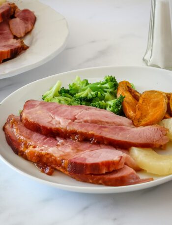 sliced baked ham on a plate with side dishes