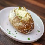 a baked potato on a plate with butter and parsley