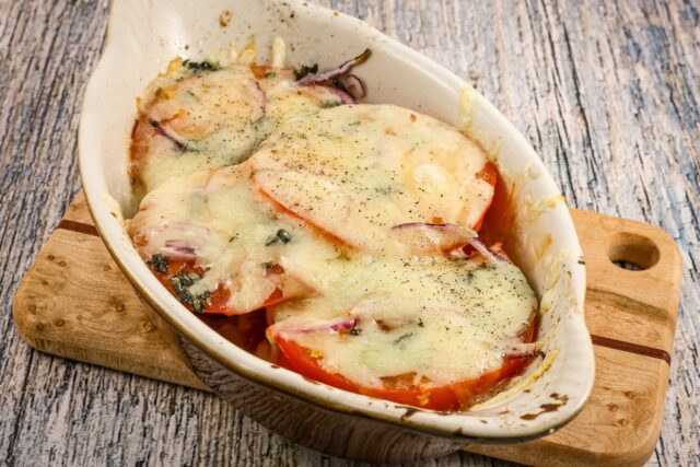 fresh baked tomatoes in a gratin dish with melted fontina cheese