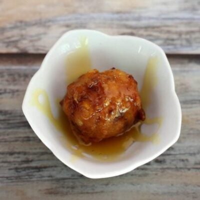 basic corn fritter in a small bowl with golden syrup