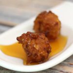 corn fritters on a small serving plate with syrup