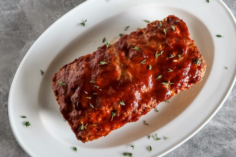 meatloaf on a platter with thyme leaves for garnish