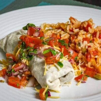 beef and bean burritos on a plate with mexican rice and salsa