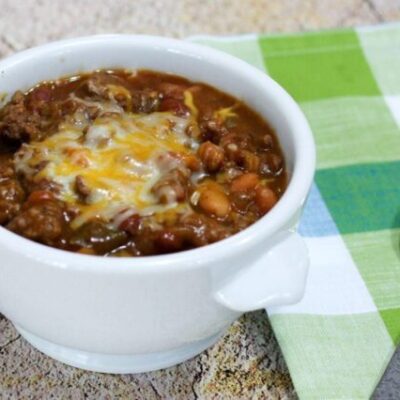beef and beans with cheese in a bowl with napkin on the side