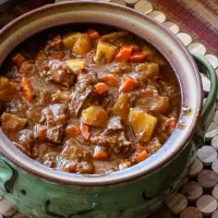 Hearty beef stew with potatoes and carrots in a rustic pot.