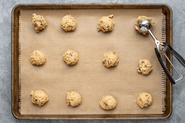 Placing cowboy cookie scoops on a baking sheet.