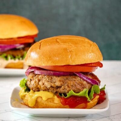 An assembled turkey burger with toppings and condiments.