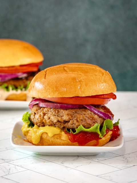 An assembled turkey burger with toppings and condiments.