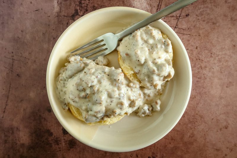A dish of split biscuits and gravy, ready to enjoy