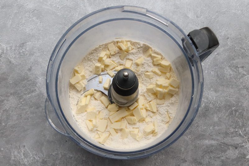 A food processor with the flour and diced butter.