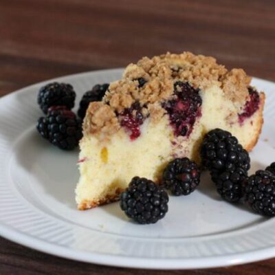 blackberry crumb cake on a plate with fresh blackberries
