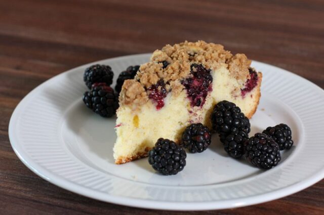 blackberry crumb cake on a plate with fresh blackberries