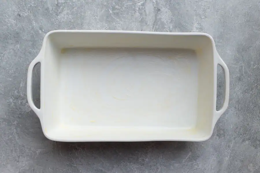 A buttered baking dish for blueberry bread pudding.