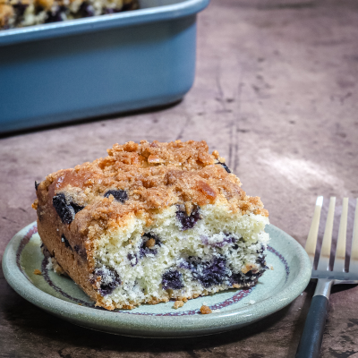 Golden blueberry crumb cake slice on a small plate.