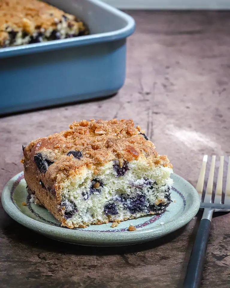 Golden blueberry crumb cake slice on a small plate.