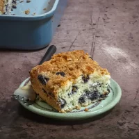 Freshly baked blueberry coffee cake slice with crumb topping.