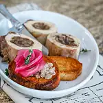 Fried bread topped with pickled onions and herbs on a white plate.