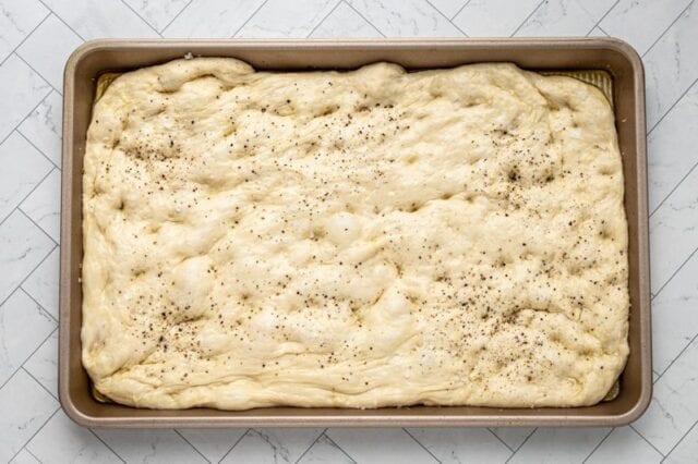 dough spread out in the pan and dimpled all over.