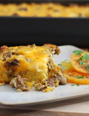 breakfast casserole with sausage on a plate with the baking dish in the background