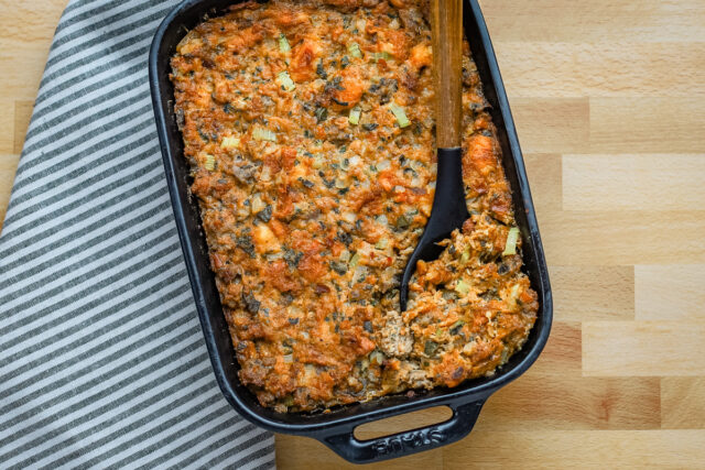 Brioche stuffing in a baking dish with sausage, herbs, and aromatics.