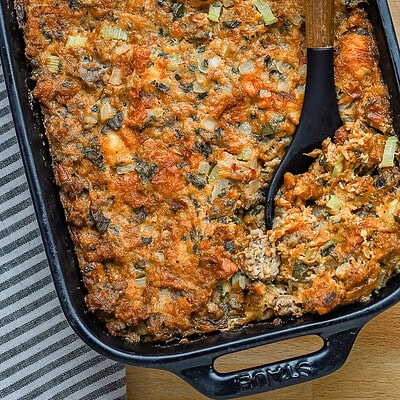 Brioche stuffing in a baking dish with sausage, herbs, and aromatics.