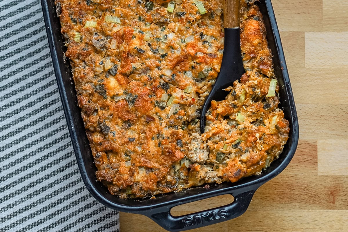 Brioche stuffing in a baking dish with sausage, herbs, and aromatics.