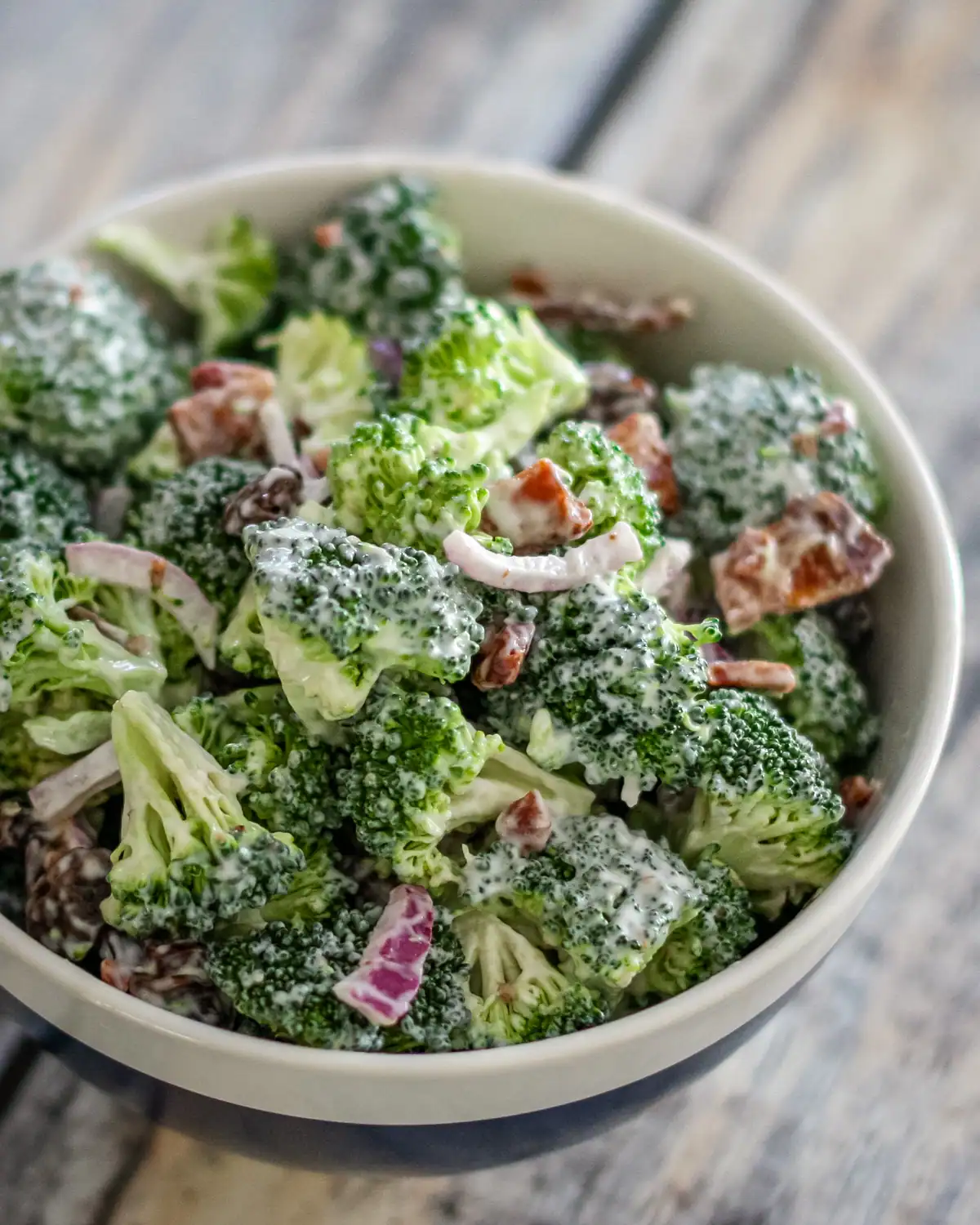 Creamy broccoli salad with red onion and bacon bits.