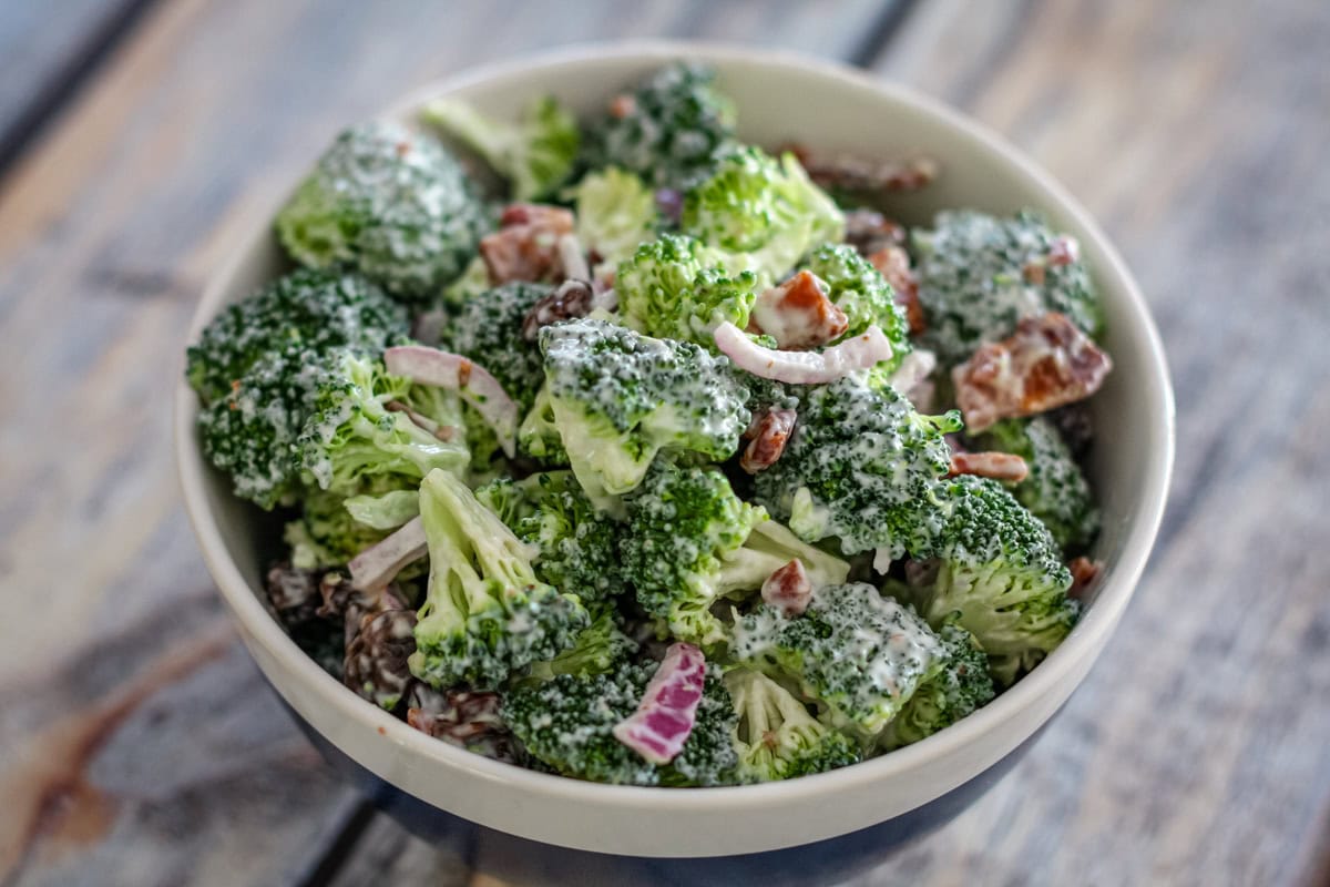 A bowl of broccoli salad with bacon, red onions, and a sweet mayonnaise dressing.