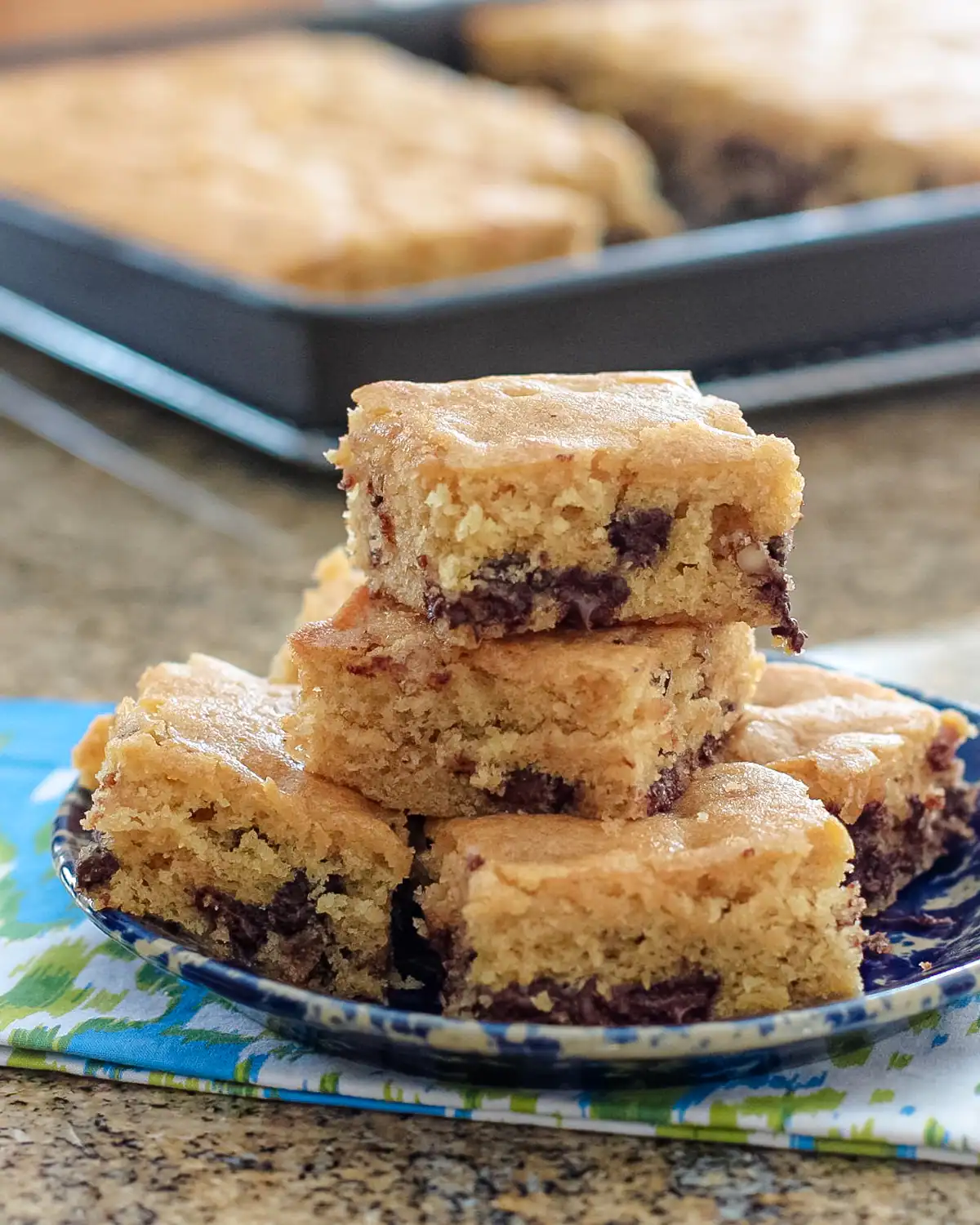Golden chocolate chip cookie bars stacked on a plate.