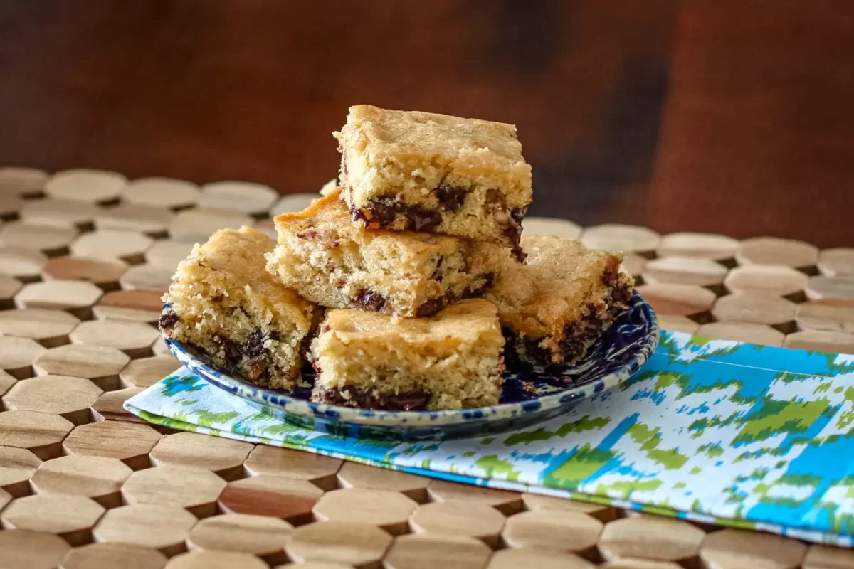 Freshly baked chocolate chip blondies stacked on a decorative plate.