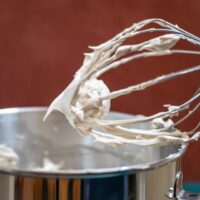 a wire whisk lifted from a bowl of brown sugar meringue