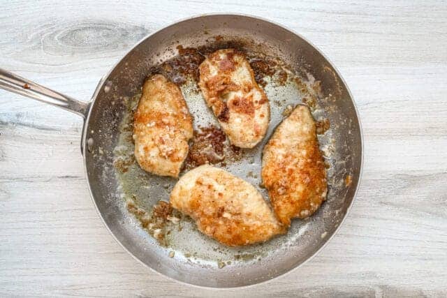 Golden-brown breaded chicken breasts in a skillet.