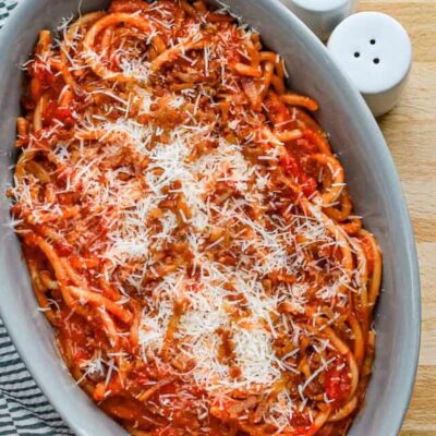 A serving bowl with bucatini all'Amatriciana topped with grated pecorino Romano and extra guanciale.