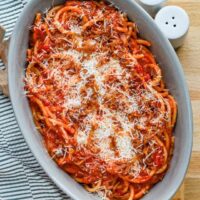 A serving bowl with bucatini all'Amatriciana topped with grated pecorino Romano and extra guanciale.