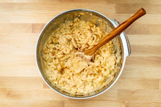 Combining the cheese sauce, chicken mixture, and macaroni for the buffalo chicken mac and cheese.