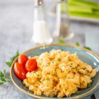 Buffalo chicken mac and cheese on a plate with some parsley and grape tomatoes.