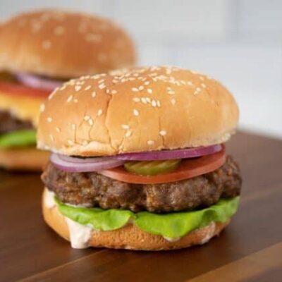 grilled burger with chipotle mayonnaise or aioli on a board with a cheeseburger in the background